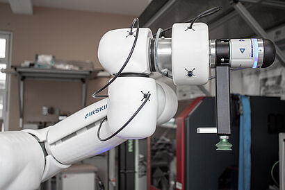 oberer Teil eines Roboterarms mit weißer Polsterung und einem Vakuum-Greifsystem