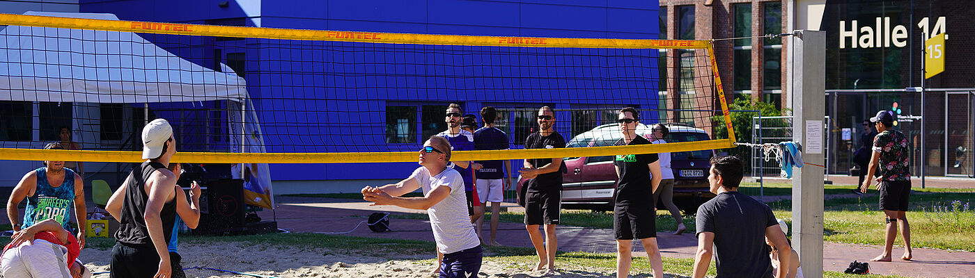 Studierende und Beschäftigte spielen Beachvolleyball auf dem Campus