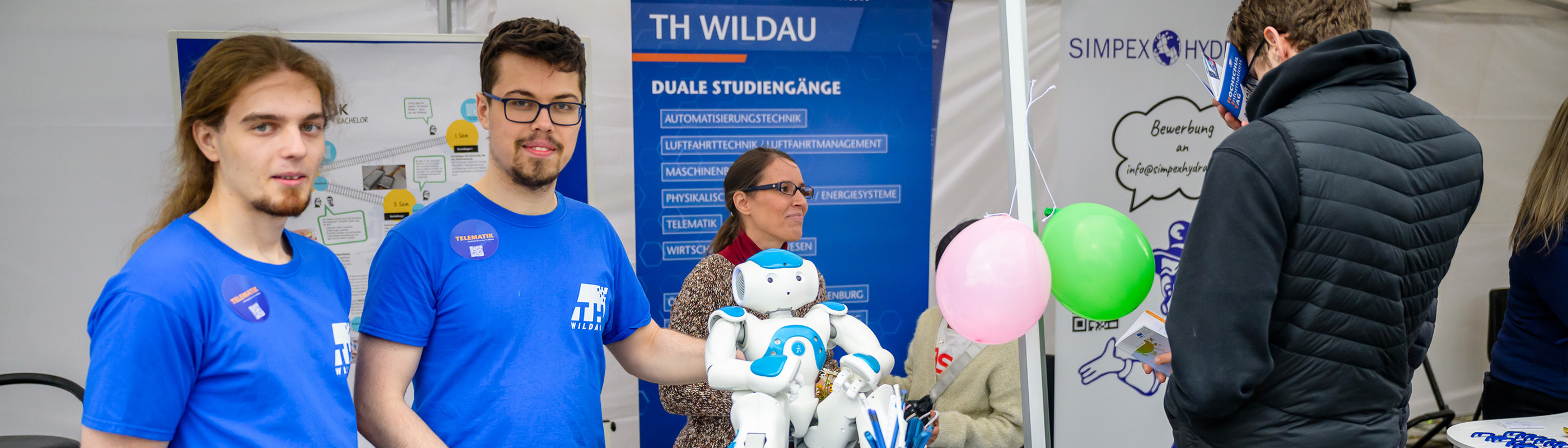 Studierende an einem Stand mit einem humanoiden Roboter beim HIT 2025