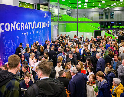 Blick in das mit zahlreichen Personen gefüllte Audimax der TH Wildau, an der Wand hängt ein Plakat mit der Aufschrift "Congratulations"