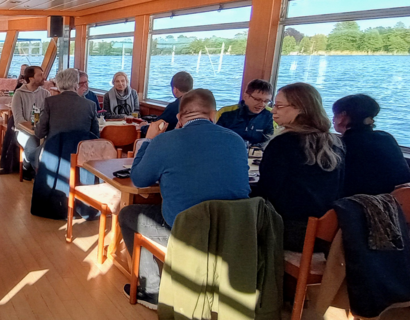 Personen sitzen an Tischen auf einem Ausflugsboot