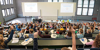 Kinder im Audimax, die sich melden