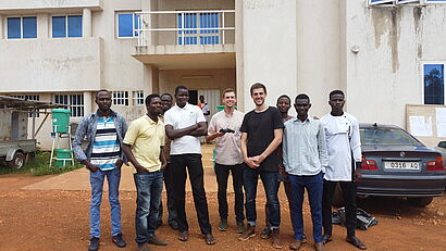 Eine Gruppe von Personen steht gemeinsam vor einem Universitätsgebäude für ein Foto.