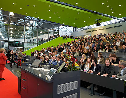 Prof. Ulrike Tippe vor einem gefüllten Audimax bei der feierlichen Verabschiedung der Absolventinnen und Absolventen 2023 des Fachbereichs WIR