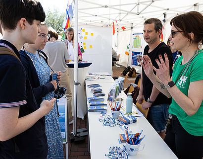 Besucherinnen und Besucher im Gespräch an einem Infostand beim Hochschulinformationstag 2023 der TH Wildau