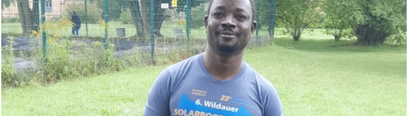 Ein Mann mit einem T-Shirt der Solarboot-Regatta steht auf einer Wiese im Freien.
