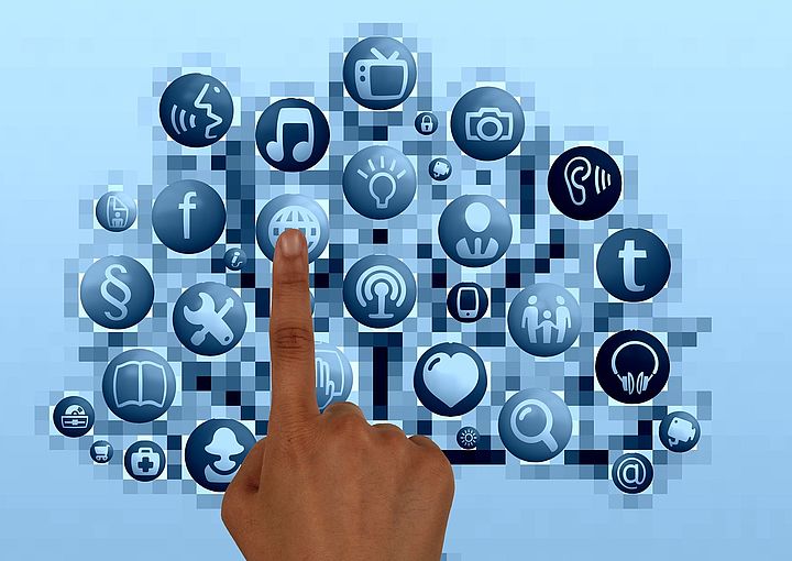 Link zu "Barrierefreie digitale Medien" - Bild zeigt einen Finger über Symbolen verschiedener Medien, wie z.B. Fotoapparat, Video, Smartphone