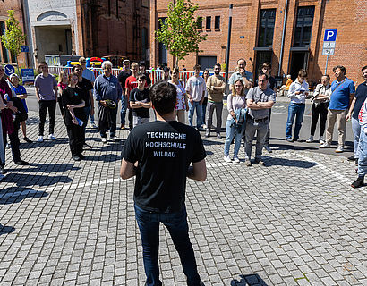 Mitarbeitender der TH Wildau steht vor einer Gruppe auf dem Campus der TH Wildau