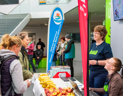 Menschen stehen an einem Tisch, darauf liegt obst