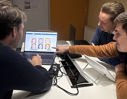 Drei Männer betrachten Laptop