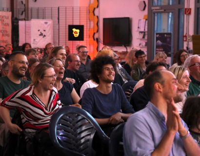 Menschen im Publikum lachen und applaudieren.