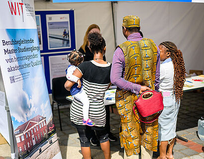 Eine Familie steht an einem Info-Stand des Wildau Institute of Technology beim HIT 2026 der TH Wildau.