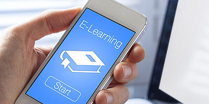 Hand mit Smartphone und E-Learning-Screen