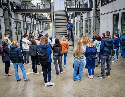 Besucher*innen stehen bei einer Campustour der TH Wildau im Kreis und lauschen dem Vortragenden