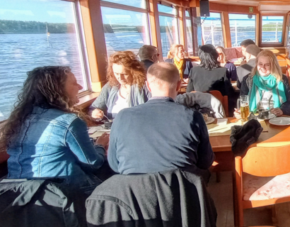 Personen sitzen an Tischen auf einem Ausflugsboot