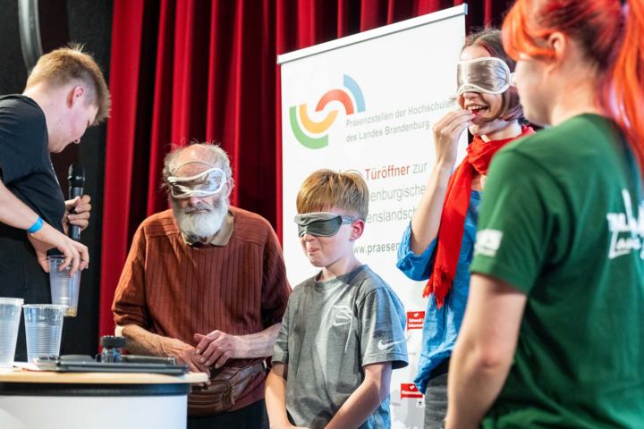 Menschen mit verbundenen Augen auf einer Bühne