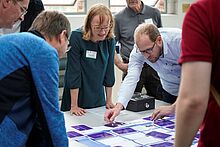 Awareness Forum 2023 Teilnehmende des Awareness Forum 2023 stehen um einen Tisch und führen zusammen ein Serious Game zum Thema Informationssicherheit durch