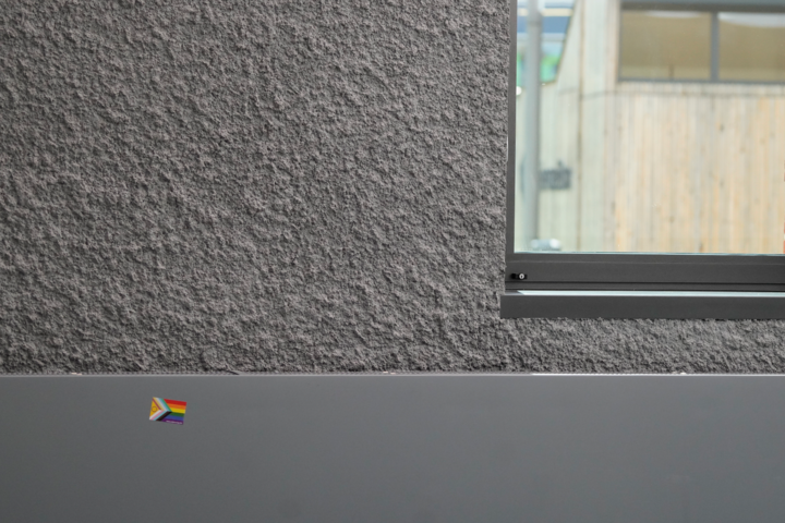 Ein Prideflag-Sticker klebt an einer Wand
