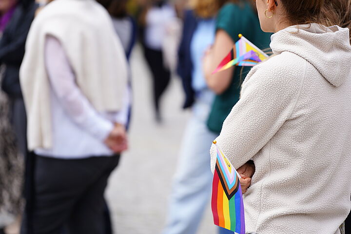 Rücken von zwei Menschen und eine kleine Regenbogenfahne