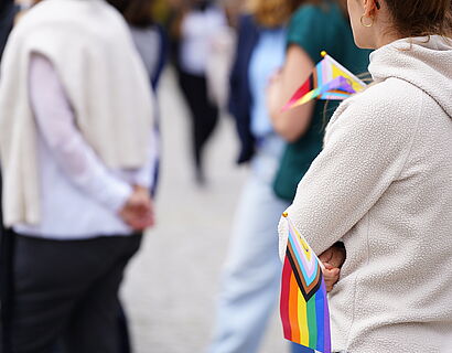 Rücken von zwei Menschen und eine kleine Regenbogenfahne