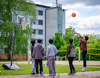 Fünf Personen auf dem Campus spielen Basketball