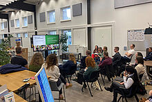 Personen sitzen auf Stühlen im Opp:Lab und verfolgen einen Vortrag