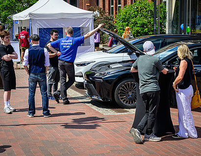 Studieninteressierte und Dozierende sind an Elektro-Autos auf dem Campus beim HIT 2026 im Gespräch