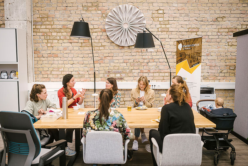 Teilnehmende & Mentorinnen sitzen am Tisch und unterhalten sich