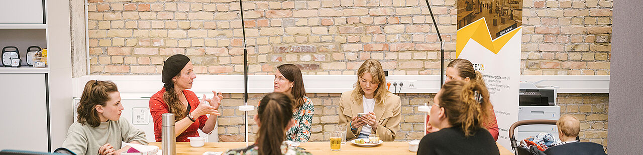 Teilnehmende & Mentorinnen sitzen am Tisch und unterhalten sich