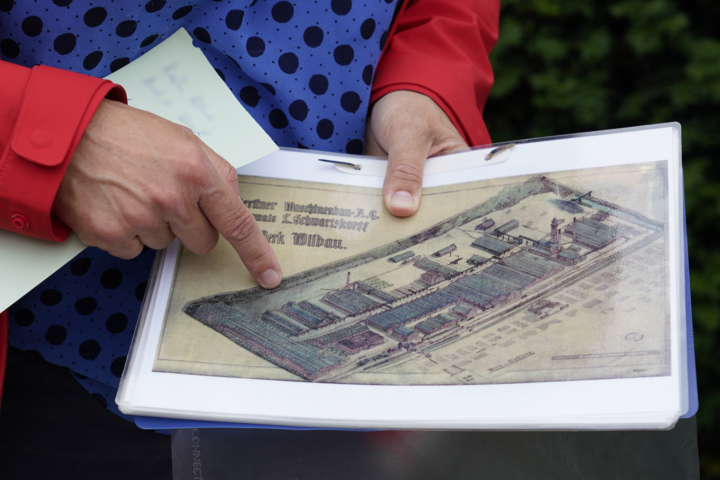 Eine historische Zeichnung einer Fabrik wird in die Kamera gehalten
