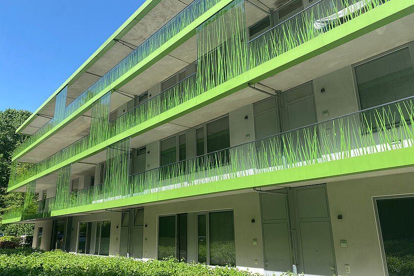 Studierendenwohnheim Gebäudeansicht eines mehrstöckigen Wohnhauses mit Balkonen und grün beklebten Balkonbegrenzungen