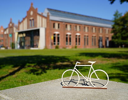 Miniatur-Fahrrad auf dem Campus, Halle 14 im Hintergrund