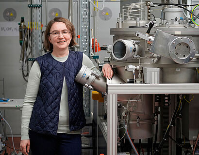 Eine Professorin lehnt an einem Laser in einem Physiklabor.