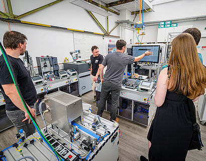 Besucherinnen und Besucher des HIT 2024 im Labor der Automatisierungstechnik. 