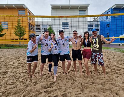 Beachvolleyball-Team posiert vor Netz