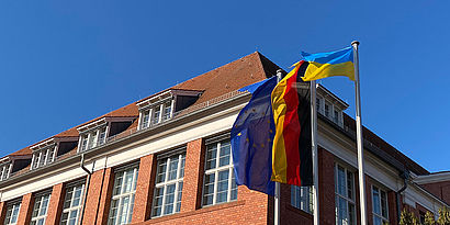 Europäische, deutsche und ukrainische Flagge vor Haus 13