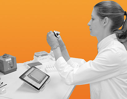 Frau sitzt im Labor vor orangenem Hintergrund