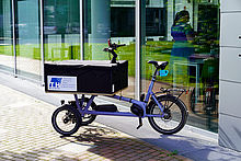 Bild eines Lastenrads mit TH-Wildau-Logo vor Haus 16 auf dem Campus