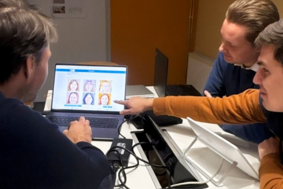Drei Personen schauen auf einen Laptop.