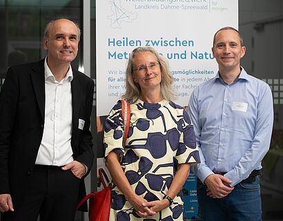 3 personen vor einem Plakat