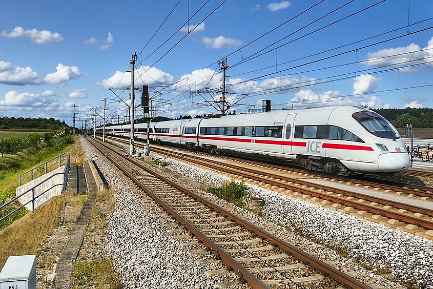 Verkehrswissenschaftliches Kolloquium ICE Zug fährt auf einer Bahnstrecke durch die Landschaft.