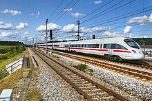 Verkehrswissenschaftliches Kolloquium ICE Zug fährt auf einer Bahnstrecke durch die Landschaft.