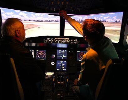 heureka-Delegation zu Besuch auf dem Campus der TH Wildau. Zwei Personen im Flugsimulator der Luftffahrttechnik