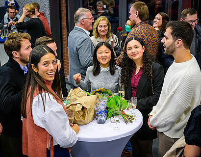 Absolvent*innen stehen gemeinsam in einer Gruppe und lachen in die Kamera