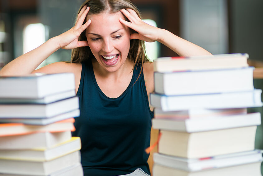 Studienzweifel Studentin mit vielen Büchern an Verzweifeln