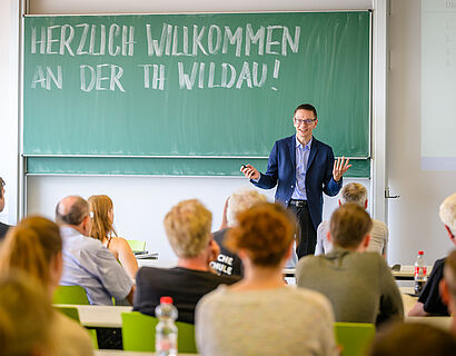 Mitarbeiter der TH Wildau vor einer Tafel im Gespräch mit Besucherinnen und Besuchern des HIT 2024. 