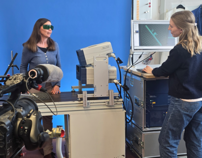 Eine Kamera im Vordergrund filmt eine Person an einem Pult