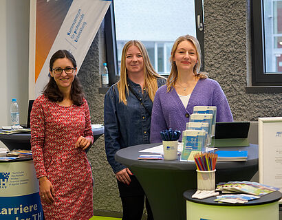 Drei Personen schauen in die Kamera an einem Stand bei der THCONNECT 2025