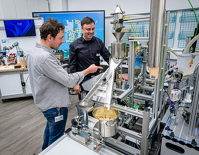 Zwei Personen stehen in einem Labor der TH Wildau an einer Popcorn-Maschine