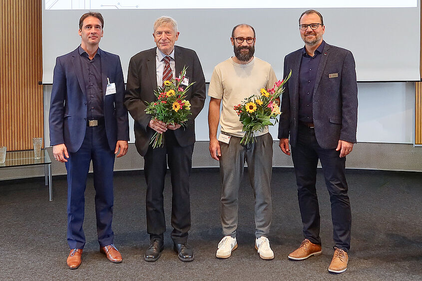 Vier Personen stehen für ein Gruppenfoto nebeneinander und haben Blumensträuße in der Hand